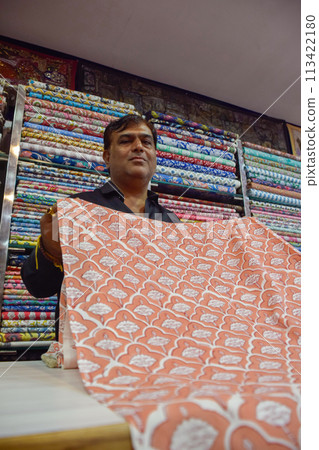 Indian seller showing textiles with variety of colors in shop of a local market 113422180