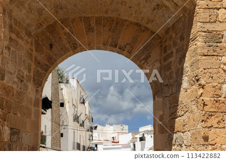 Through Almudaina Castle arch, the quaint old town of Eivissa, set against gathering clouds 113422882