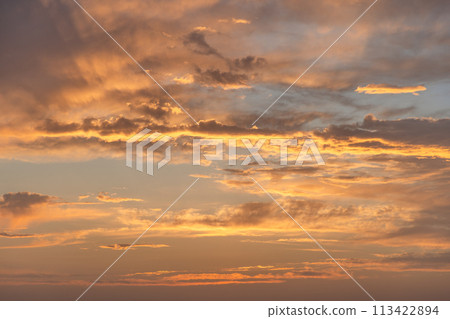 Ethereal gold and amber dusk sky, scattered clouds perfect for creative projects 113422894