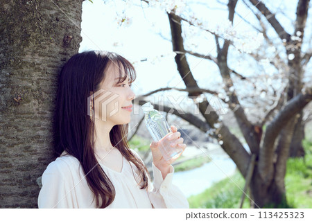 A woman drinking water under the cherry blossoms 113425323