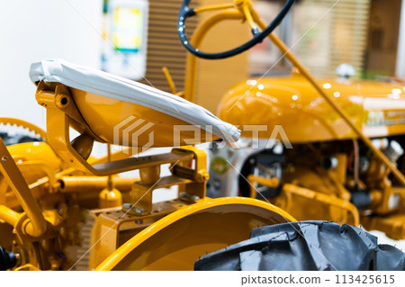 Small yellow tractor in exhibition, closeup details, wheels 113425615