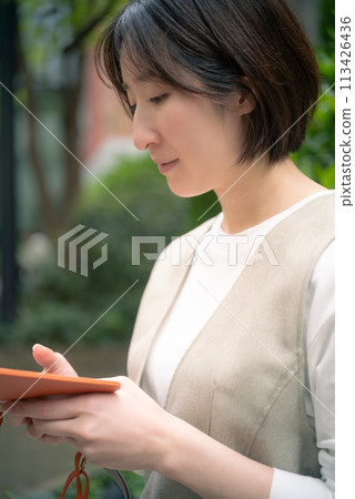 A woman searching for a store in Marunouchi, Tokyo on her smartphone 113426436
