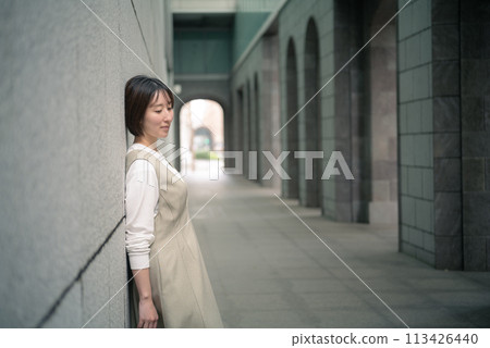 A woman leaning against a wall 113426440