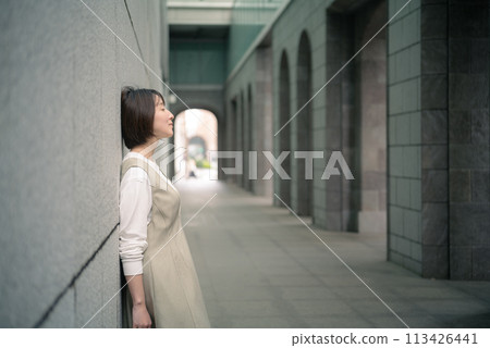 A woman leaning against a wall 113426441