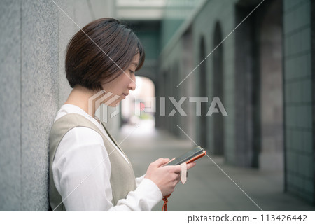 一名女子用智慧型手機搜尋東京丸之內的一家商店 113426442