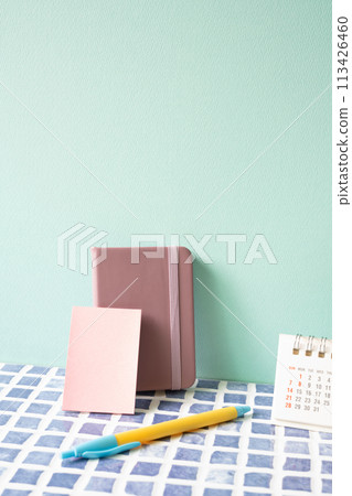 Diary note, pen, and calendar on blue tile desk. mint wall background. workspace 113426460
