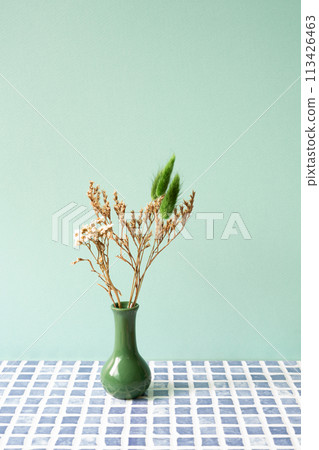 Green vase of dry flower on blue tile table. mint wall background 113426463