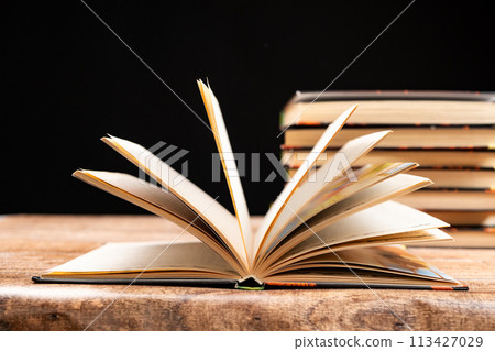 Stack of books on black background, open book. 113427029