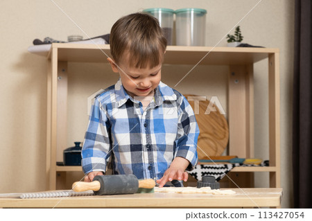 A two-year-old boy cooking in the kitchen, making dough. Cooking and kids A two-year-old boy cooking in the kitchen, making dough. Cooking and kids 113427054