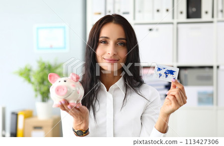 Smiling woman holding piggy bank and bank card 113427306