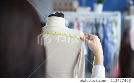 Fashion designer stylist takes measurements with centimeter from clothes on mannequin 113427498