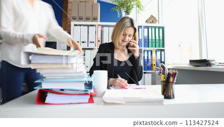 Businessman talking on phone secretary taking documents in office Businessman talking on phone secretary taking documents in office 113427524