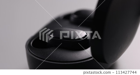 Black electronic bluetooth headphones and technical cases on grey background Black electronic bluetooth headphones and technical cases on grey background 113427744