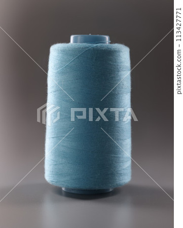Texture of blue thread in sewing spool on gray background. closeup 113427771