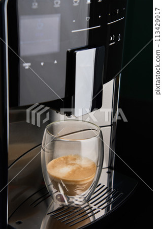 Modern automatic coffee machine with freshly brewed coffee in glass cup. Kitchen appliances Modern automatic coffee machine with freshly brewed coffee in glass cup. Kitchen appliances 113429917