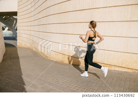 Fit woman athlete in sportswear is running on modern buildings background. Active lifestyle concept Fit woman athlete in sportswear is running on modern buildings background. Active lifestyle concept 113430692
