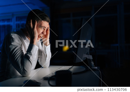 Angry office worker male working late at night and looking at computer while screaming alone. Furious man working at workplace night crazy and mad shouting, yelling with aggressive expression Angry office worker male working late at night and looking at computer while screaming alone. Furious man working at workplace night crazy and mad shouting, yelling with aggressive expression 113430706