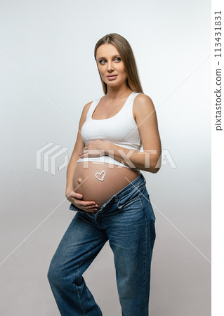 Pregnant woman putting cream on her belly and looking enjoyed Pregnant woman putting cream on her belly and looking enjoyed 113431831
