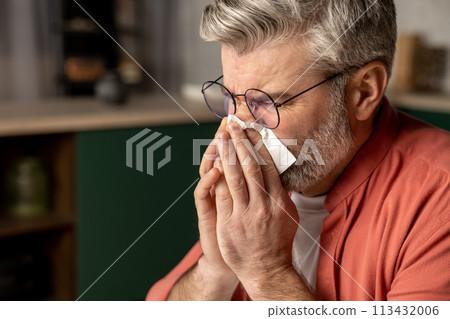 Sick middle aged grey haired man with fever and runny nose using handkerchief Sick middle aged grey haired man with fever and runny nose using handkerchief 113432006