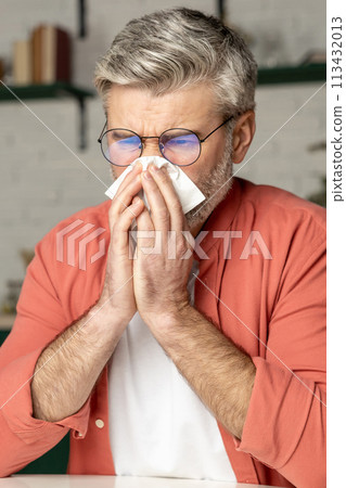 Unhealthy man sneezing with handkerchief suffering from cold flu 113432013