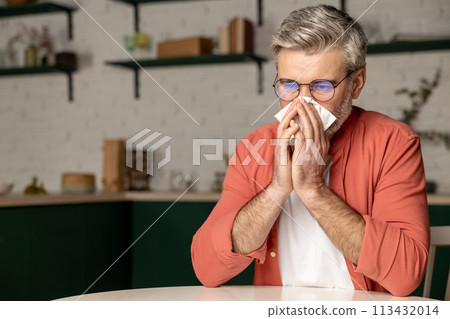 Sick middle aged grey haired man with fever and runny nose using handkerchief Sick middle aged grey haired man with fever and runny nose using handkerchief 113432014