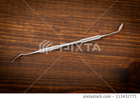 Dental hygienist instrument on a dark wooden background. Learning and professionalism 113432771