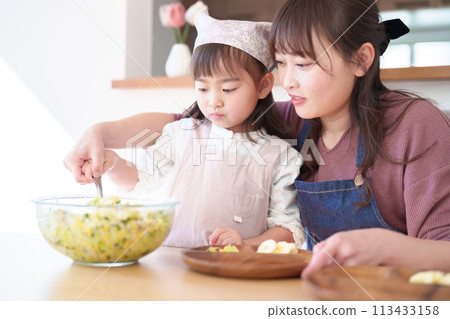 Girl and mother preparing dinner Girl and mother preparing dinner 113433158
