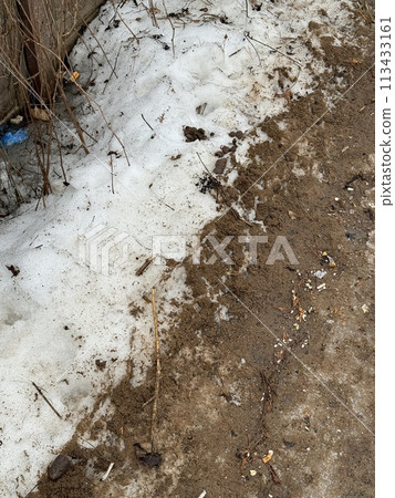 Melting dirty snow on the streets of the city during the daytime in winter. Snow with sand and mud lies on the road. Melting dirty snow on the streets of the city during the daytime in winter. Snow with sand and mud lies on the road. 113433161