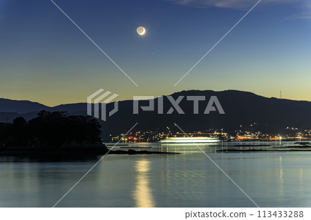 A crescent moon and a ferry light trail sinking in the Seto Inland Sea in the afterglow A crescent moon and a ferry light trail sinking in the Seto Inland Sea in the afterglow 113433288