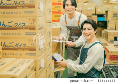 A worker in an apron doing light work in a warehouse 113433311