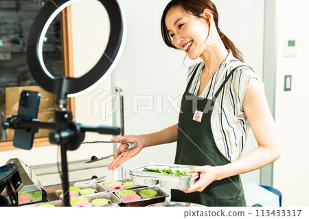 A female influencer cooking in a video broadcast 113433317