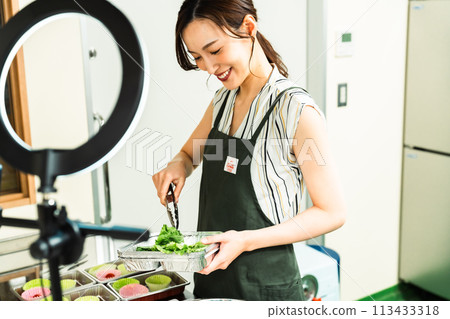 A female influencer cooking in a video broadcast 113433318