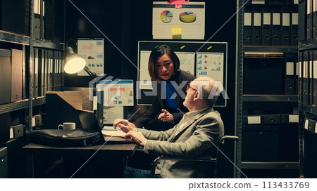 Detectives team comparing witness statements in investigations, reopening old case files to cross reference data and search for connections. Paralyzed inspector works with law agent. Camera A. Detectives team comparing witness statements in investigations, reopening old case files to cross reference data and search for connections. Paralyzed inspector works with law agent. Camera A. 113433769