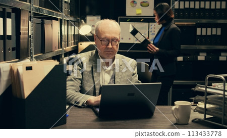Senior inspector identifying patterns in criminal behavior by analyzing classified files and legal documents. Private detective looking at forensic evidence in hope on finding clues. Camera B. 113433778