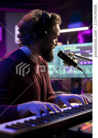Sound engineer playing piano keyboard to compose new music, singing on microphone and adding audio effects in post production. Artist composer creating songs for music industry. 113434006