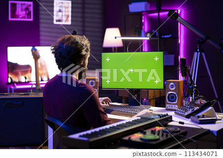 Sound engineer learning to mix and master audio recordings by watching post production tutorials online on pc with greenscreen. Artist editing tunes and adjusting volume levels in home studio. Sound engineer learning to mix and master audio recordings by watching post production tutorials online on pc with greenscreen. Artist editing tunes and adjusting volume levels in home studio. 113434071