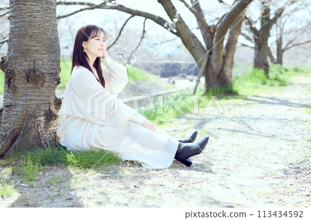 Woman sitting under cherry blossoms Woman sitting under cherry blossoms 113434592
