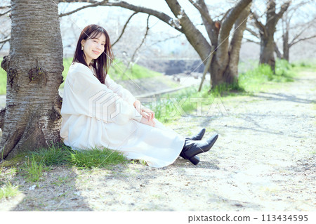 Woman sitting under cherry blossoms 113434595