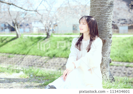 Woman sitting under cherry blossoms Woman sitting under cherry blossoms 113434601