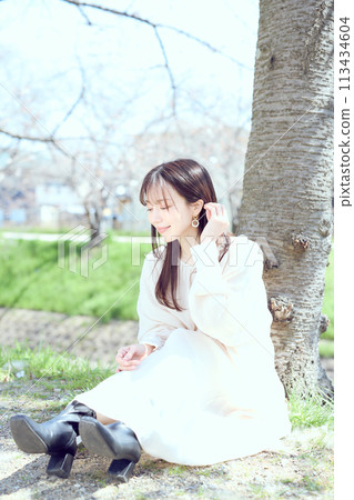 Woman sitting under cherry blossoms Woman sitting under cherry blossoms 113434604