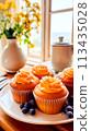 A plate of cupcakes with frosting and blueberries on a table, AI 113435028