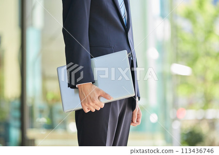 商業形象：一個穿著西裝的年輕人拿著電腦的手 113436746