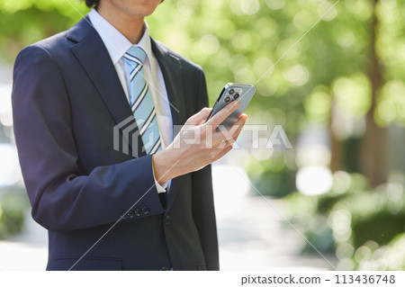 商業形象：穿著西裝的年輕人手拿著智慧型手機 113436748
