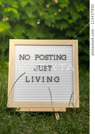 Letter board with text NO POSTING JUST LIVING in grass green background. Concept of digital detox, unplugging from technology break. Mindful living 113437950