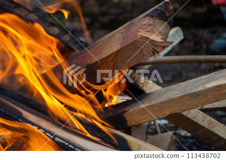 A fire burns in a campfire with a red fire in the background. A fire burns in a campfire with a red fire in the background. 113438702
