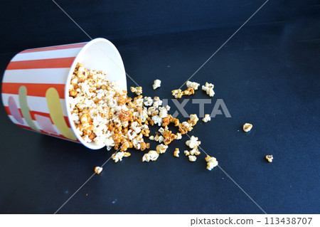 A striped bucket with flying popcorn isolated on a white background. 113438707