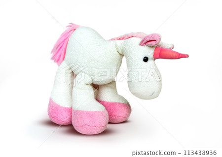 Pink soft unicorn toy sitting at white background. Isolated studio image 113438936