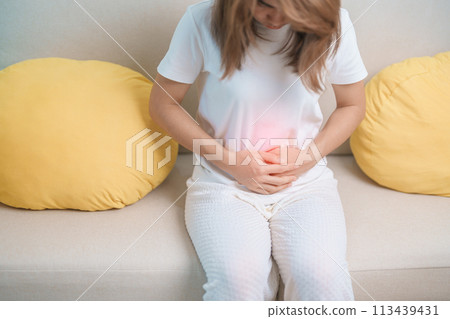 woman having abdomen ache due to Stomach pain, digestion with constipation or Diarrhea from food poisoning, female problem and Endometriosis, Hysterectomy, Stomachache and Menstrual on sofa at home 113439431