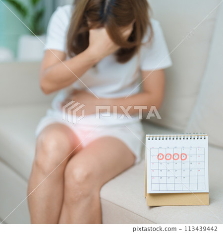 Menstruation period cycle of monthly and Stomachache concepts. woman having abdomen pain with calendar, illness female suffer from premenstrual ache and body Health problem on sofa at home 113439442