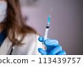 Close-up of a syringe with liquid in the hand of a doctor of a woman in a blue glove 113439757